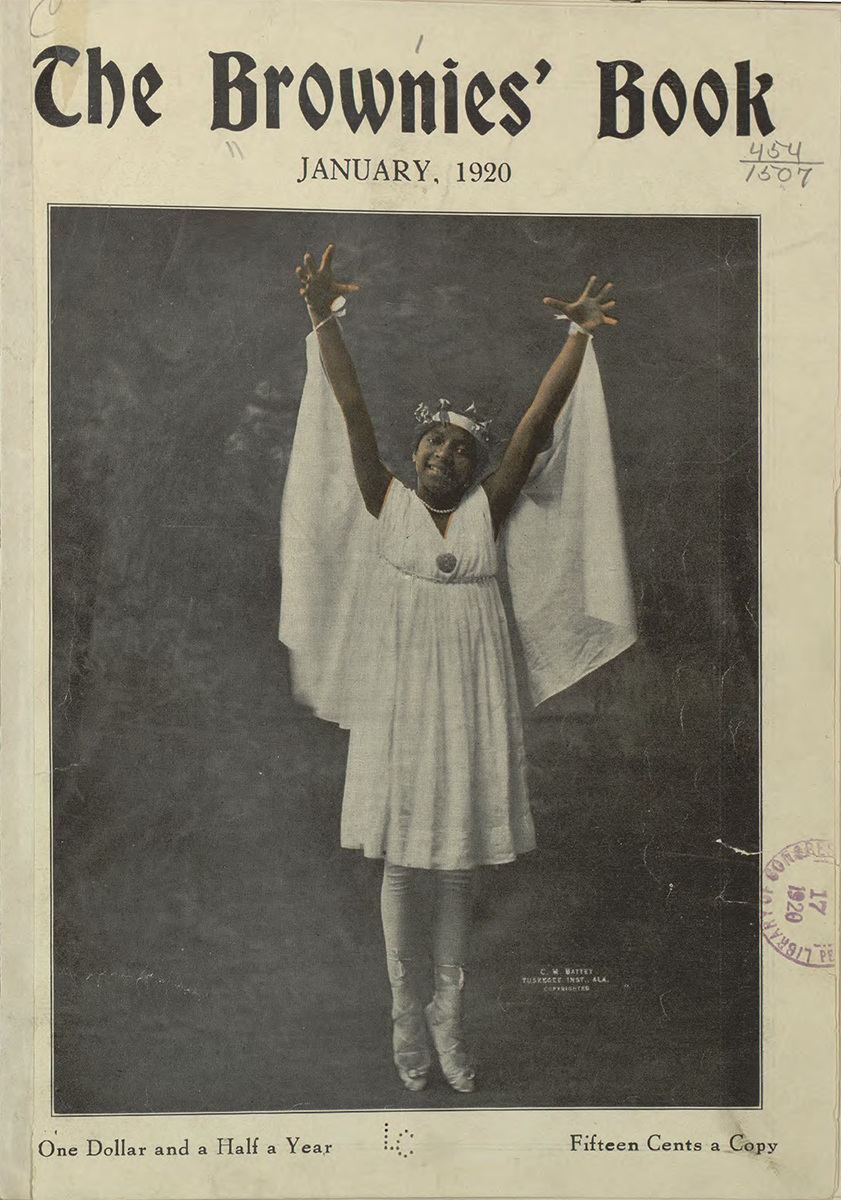 A young black girl smiles and poses, arms outstretched and standing on ballet pointe shoes. She wears a white dress, crown, and cape tied at her wrists.
