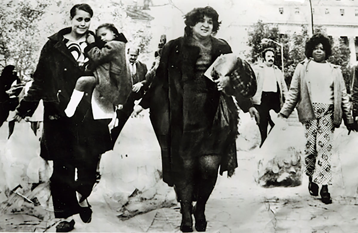 Parents protest poor school lunch quality at Federal Plaza in Manhattan. One woman carries a child and other parents carry garbage bags of food.