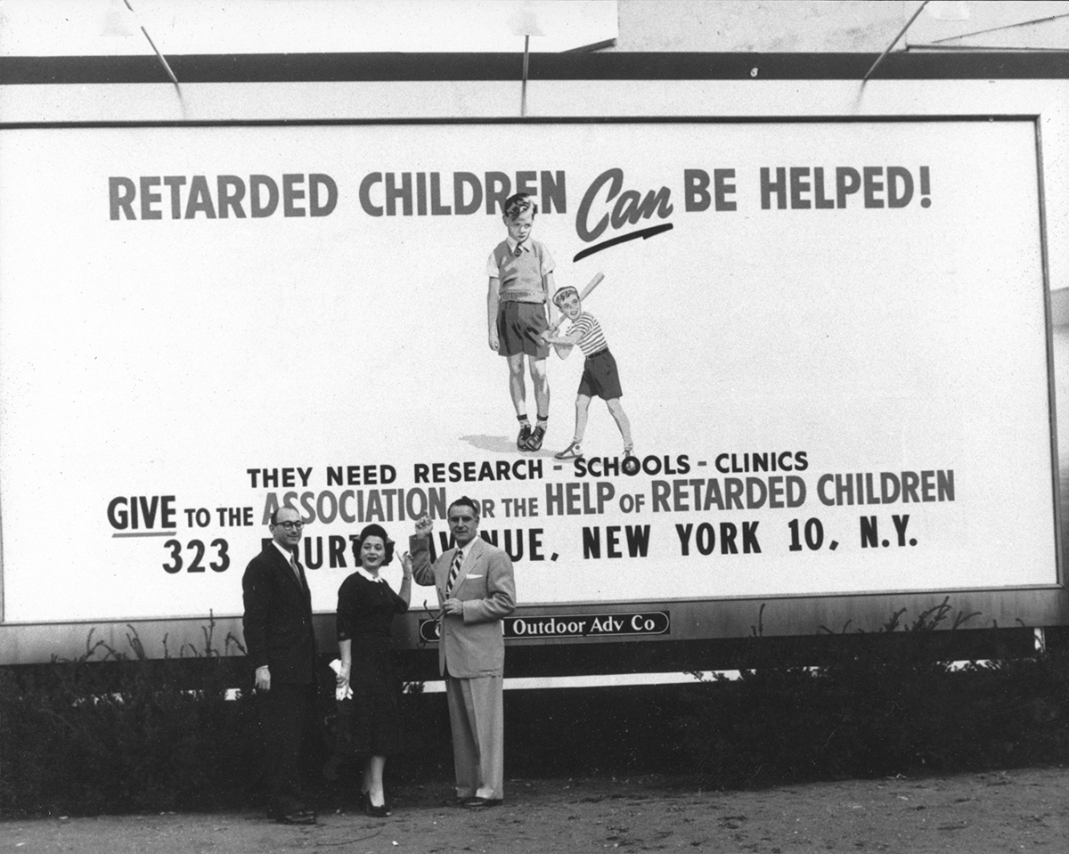 Parent activists in front of a billboard that reads, "Retarded Children Can be Helped! They need Research, Schools, Clinics. Give to AHRC"